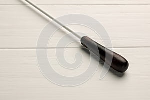 Conductor`s baton on white wooden table, closeup photo