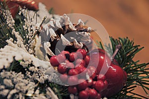 Cone and branches of a Christmas tree under snow, red berries.