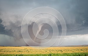 A cone tornado spins over the open landscape of the Great Plains.