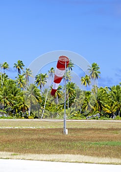 Cone wind measure wind direction in small airfield on the tropical island with palm trees at a runway