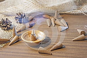 Cones Incense smoke in a ceramic stand on a wooden table.