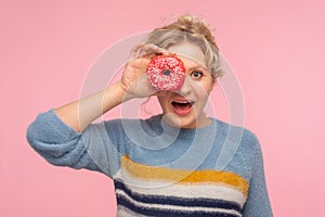 Confection, sweet dessert. Portrait of surprised woman holding doughnut, looking through donut at camera with amazement