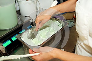 Confectioner in chef uniform is working at ice cream factory. Woman is decorations of italian creamy mint ice cream flavors.