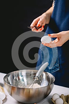 Confectioner cracking an egg into steel dish