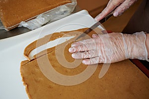 A confectioner cuts strips of gingerbread dough with a kitchen knife on his work table. Manual preparation. Technology