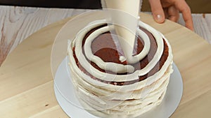 Confectioner decorates cake with cream from the pastry bag
