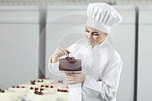 Confectioner decorating chocolate cake in pastry shop. photo