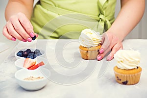 Confectioner decorating cupcake with blueberry. Cooking class, culinary and bakery. Desserts