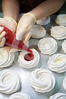 Confectioner filling the merengue nests with fresh strawberry curd photo