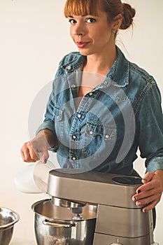 Confectioner girl in a denim shirt is preparing a cake. Concept ingredients for cooking flour products or dessert.