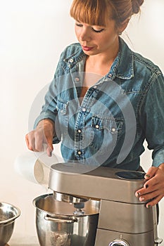 Confectioner girl in a denim shirt is preparing a cake. Concept ingredients for cooking flour products or dessert.