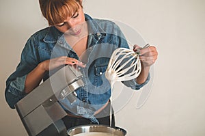 Confectioner girl holding an electric whisk is preparing a cake. Concept ingredients for cooking flour products or dessert
