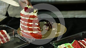 Confectioner hands cut down homemade red decorated cake