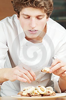 Confectioner lays out cookies and cakes on plate photo