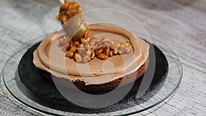 The confectioner making chocolate cake with caramel peanuts. Step by step assembly chocolate ceke.