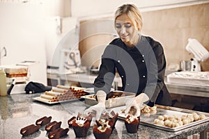 Confectioner pastry woman preparing eclairs and cupcakes