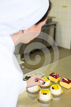 Confectioner preparing cakes at bakery or confectionery