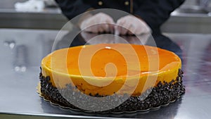 A confectioner pushes a fresh made orange cake to the front on a table