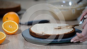 Confectioner puts cream to top of cake. Baker smoothing cake with cream icing.