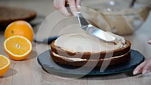 Confectioner puts cream to top of cake. Baker smoothing cake with cream icing.