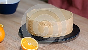 Confectioner puts cream to top of cake. Baker smoothing cake with cream icing.