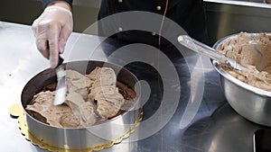 A confectioner puts and spreads a cream over a base cake