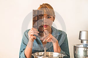 Confectioner redhead girl holds chocolate while covering her face. Concept ingredients for cooking flour products or dessert