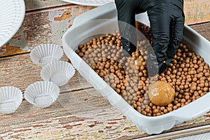 Confectioner rolling the brigadeiro brigadier of dulce de leche on salty crunchy caramels photo