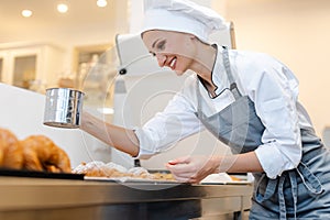 Confectioner woman powdering cocoa on sweet bread