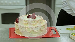 Confectioners cooking cream cake. Placing of jellied strawberry