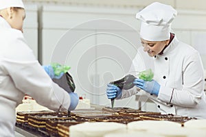 A confectioners squeezes liquid cream from a pastry bag.