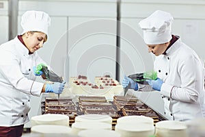 A confectioners squeezes liquid cream from a pastry bag.