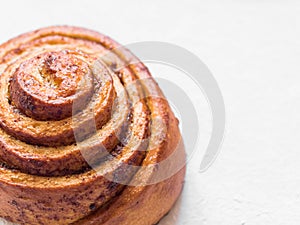 Confectionery baking. Sweet fresh soft roll bun with cinnamon on white background. Cinnabon closeup