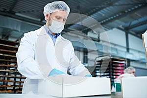 Confectionery factory employee preparing package