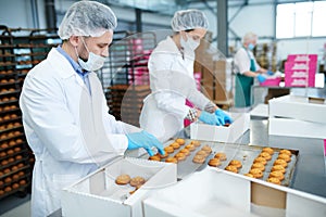Confectionery factory workers putting pastry into boxes
