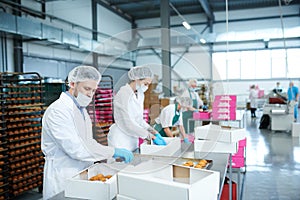 Confectionery factory employees putting pastry into boxes