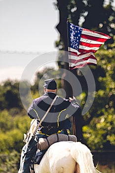 Confederate reenactor riding a horse with a flag of the United States at the Civil War reenactment