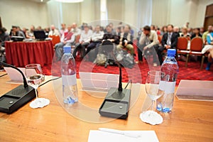 Conference in hall. bottle, microphone on table