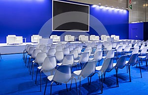 Conference Meeting Room, Row of White Chairs, with Stage and Empty Screen
