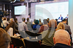 Conference participants, events, presentations, listen to the speaker sitting in chairs.