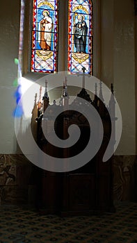 Confessional below a stained glass window in a church