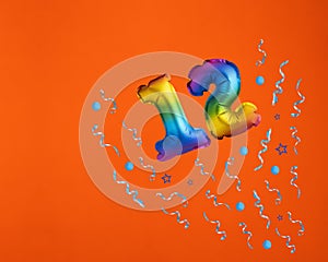 Confetti explosion with number 12 balloon - Celebration on orange background. Birthday card