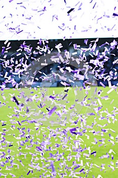 Confetti falling from the sky after a victory with a rugby field in the background.