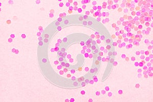 Confetti on pink paper background, festive concept.