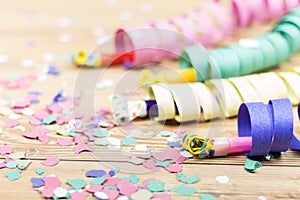 Confetti, streamers and party blower on wood background