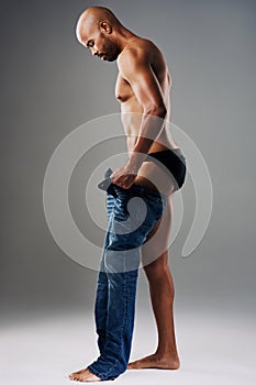 Confidence is the best outfit to rock. Full length shot of a handsome young man undressing against a grey background.