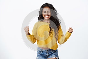Confidence, business and wellbeing concept. Successful cheerful african american curly-haired girl fist pump and smiling