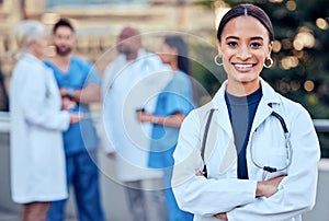 Confidence, crossed arms and portrait of a female doctor with her team outdoor at the hospital. Leadership, smile and