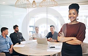 Confidence got me this far. Portrait of a young businesswoman standing in an office with her colleagues in the