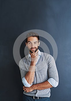 Confidence is key. Portrait of a handsome young businessman posing against a dark background.